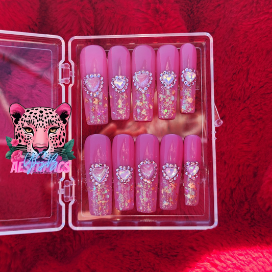A set of press-on nails in a pink case, adorned with opal heart stones and glitter, with a leopard logo on the front. Luxury handmade press-on nails by YSB Aesthetics BLUSHING BOWS LUXURIOUS PRESS-ON NAILS
